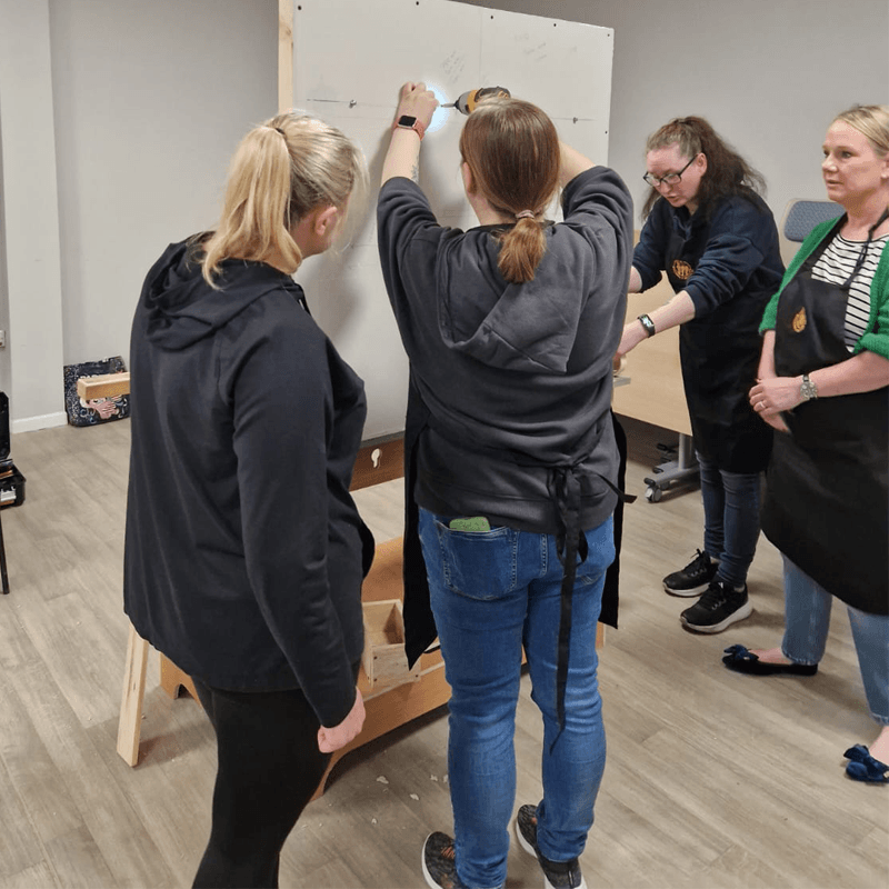women drilling in a wall for DIY classes for women