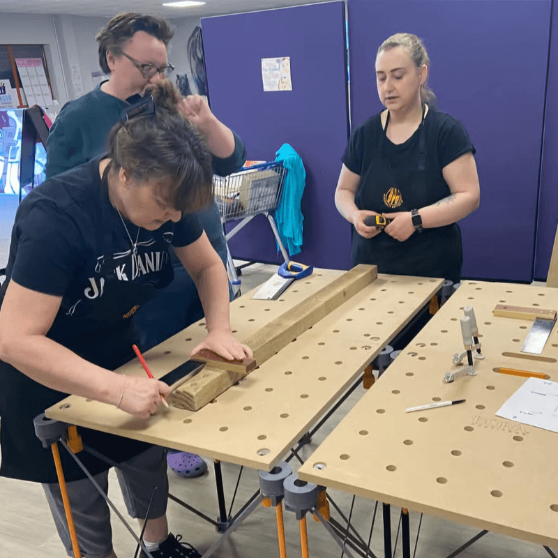 Three Grils in the DIY Classes for women working on a table bilding a wooden Fram