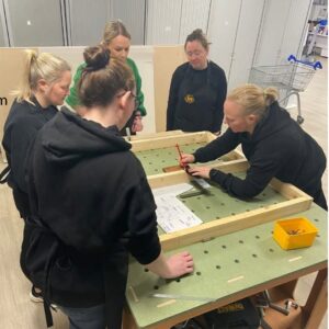 Sarh demonstrating to a group of students how toi use an square