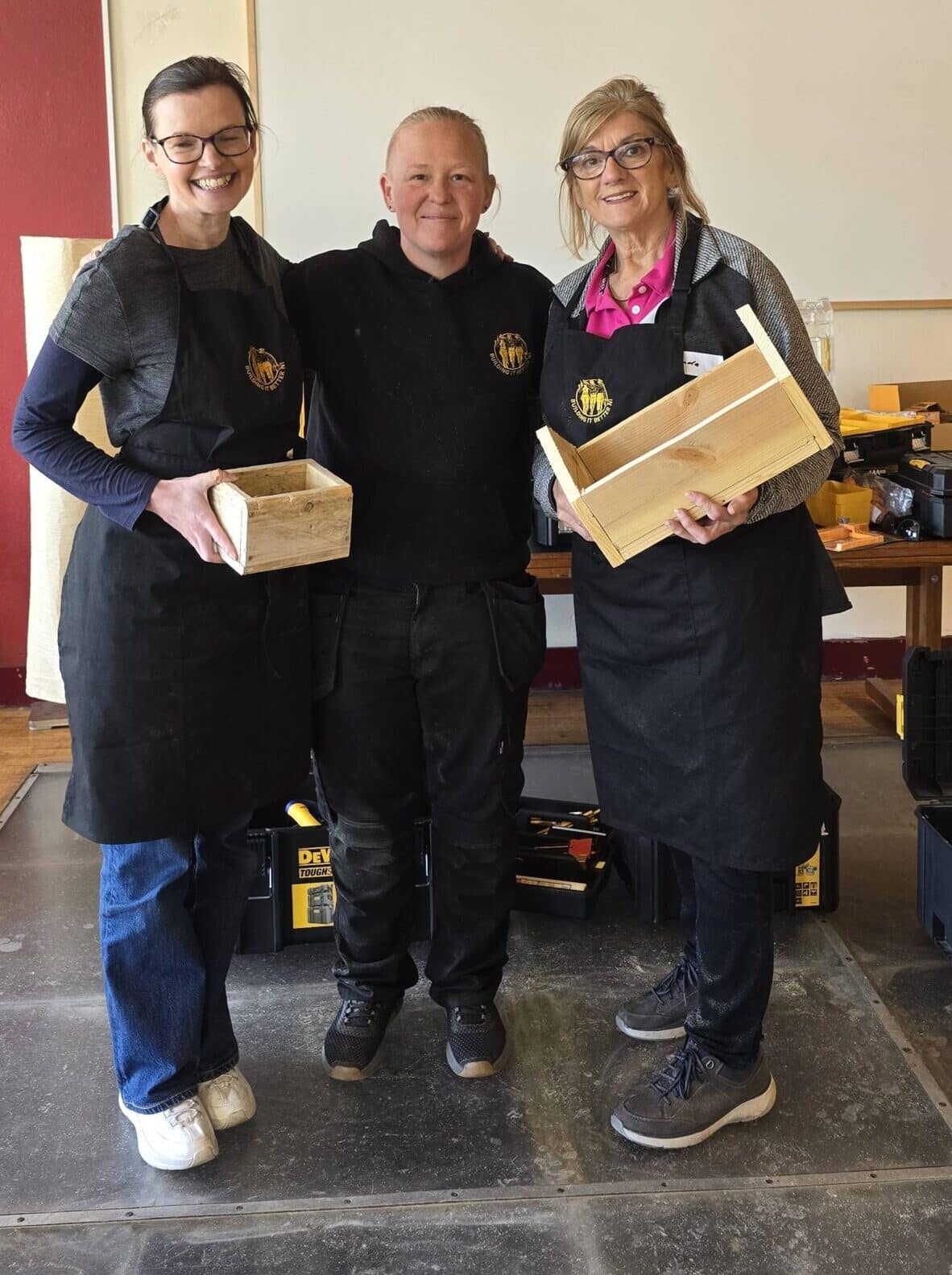 two women proudly show of thier project with the CEO from one of the DIY classes for women